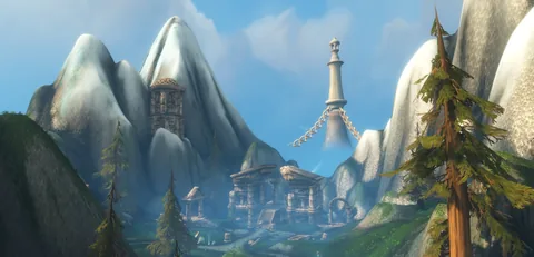 Snowy peaks behind a white tower and stone buildings